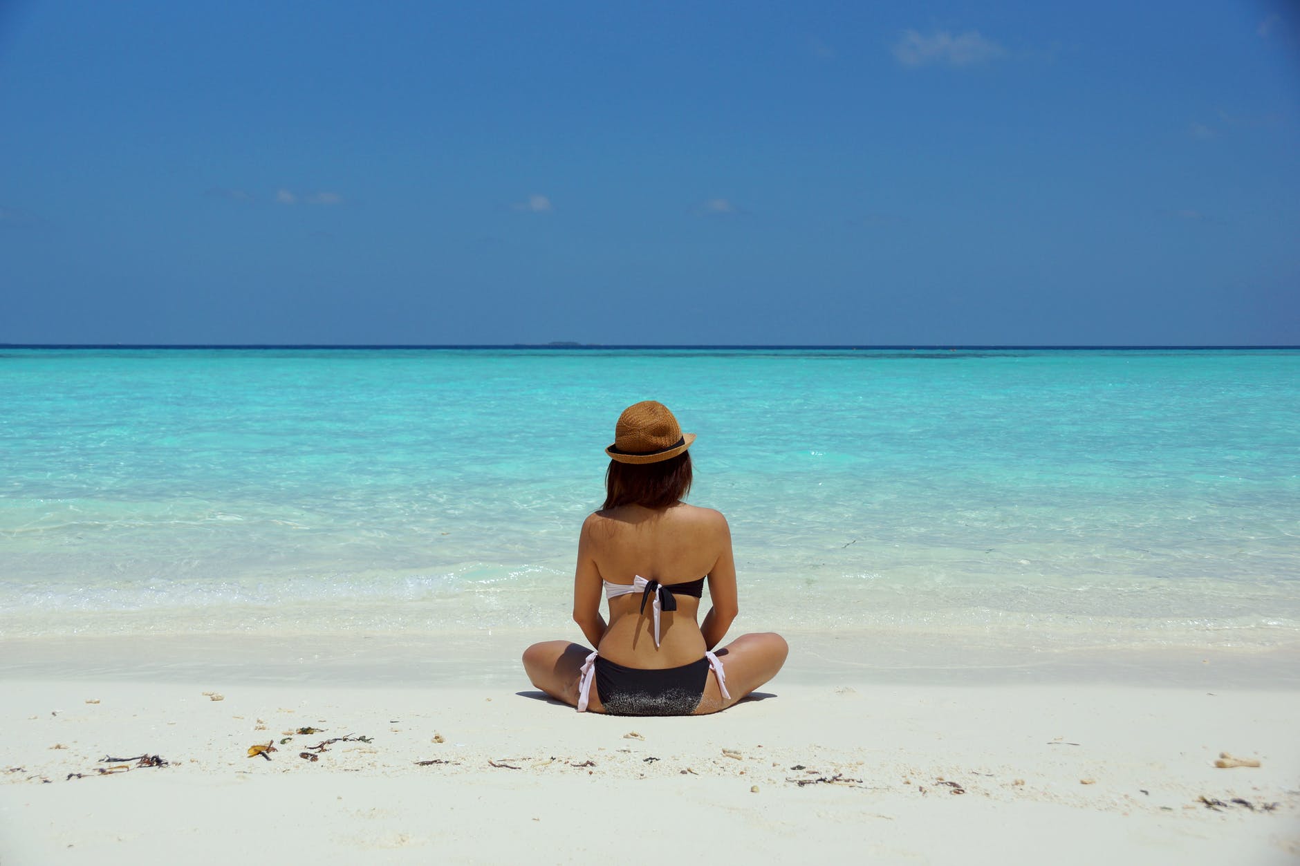 woman wearing black and white brassiere sitting on white sand