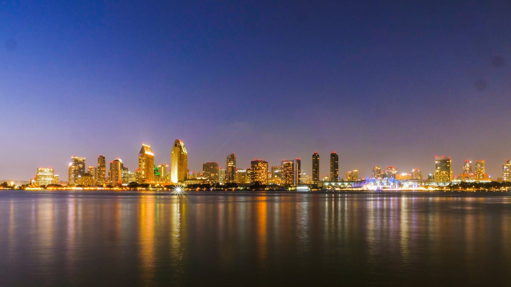 city skyline across body of water during night time