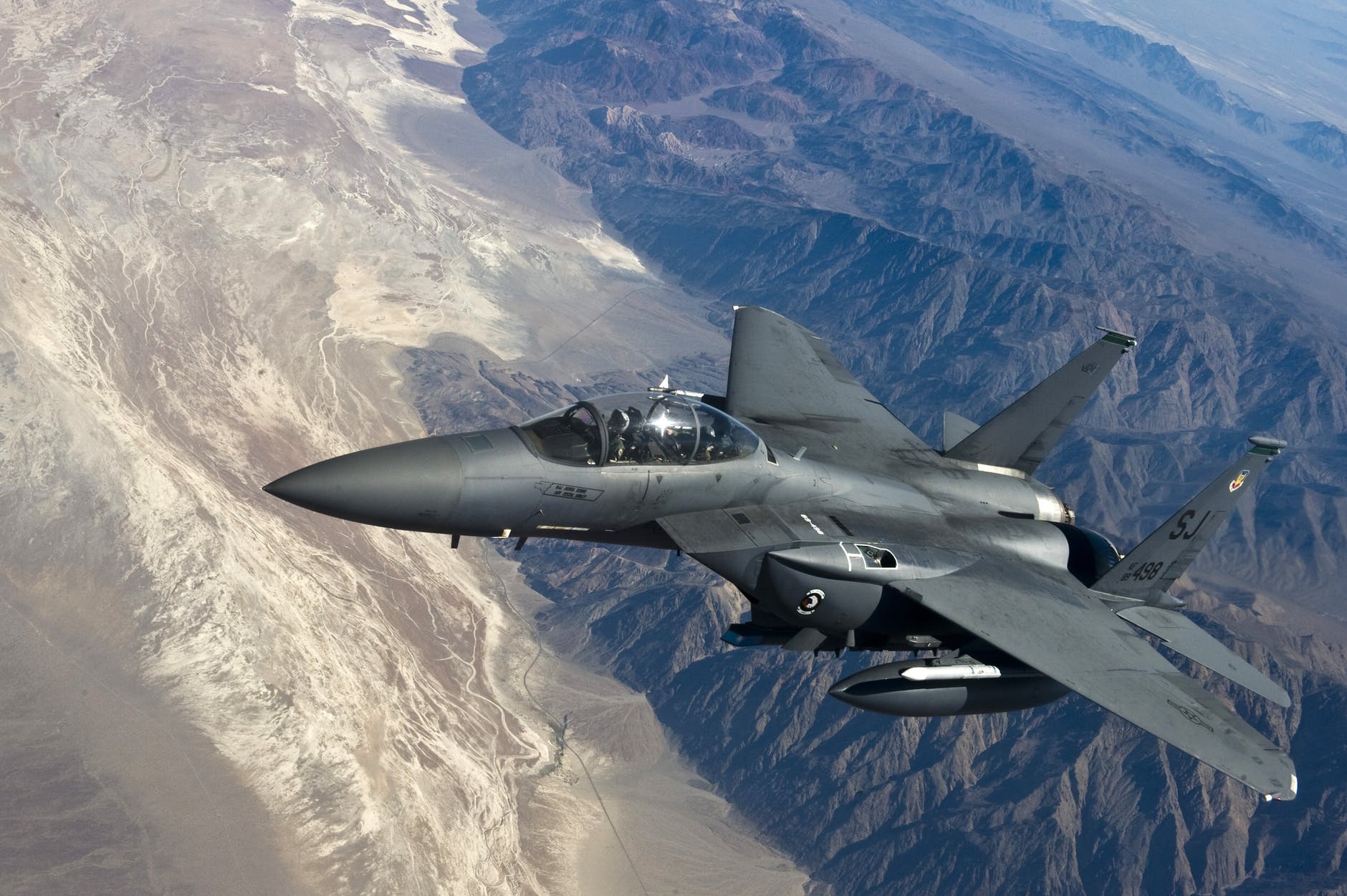 grey jet plane flying on top of white mountain