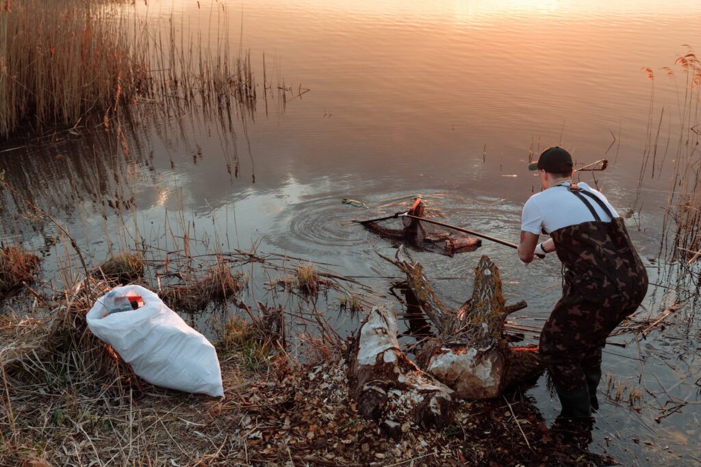 a man scooping trash in a lake