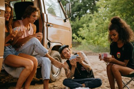 a group of friends playing cards by a campervan