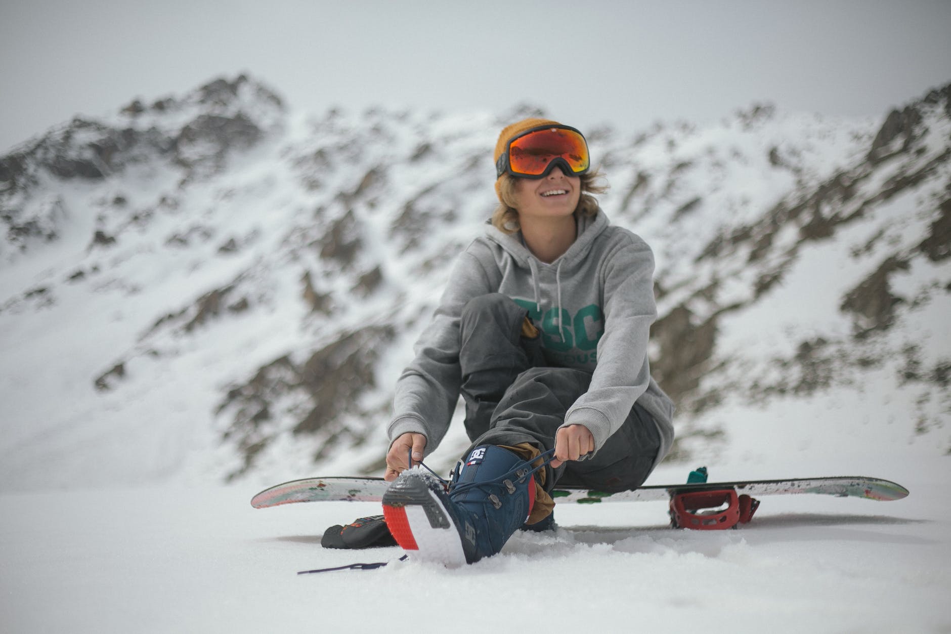 person in grey hoodie sitting on snowboard