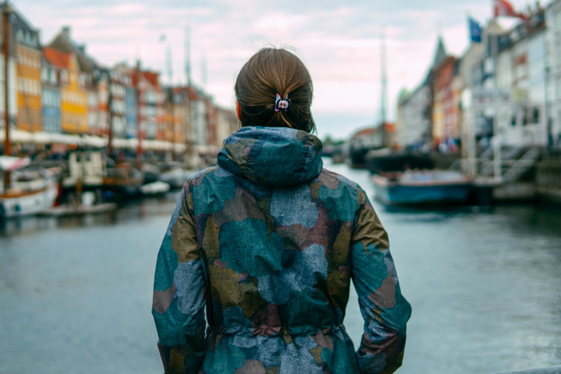 woman beside river between buildings