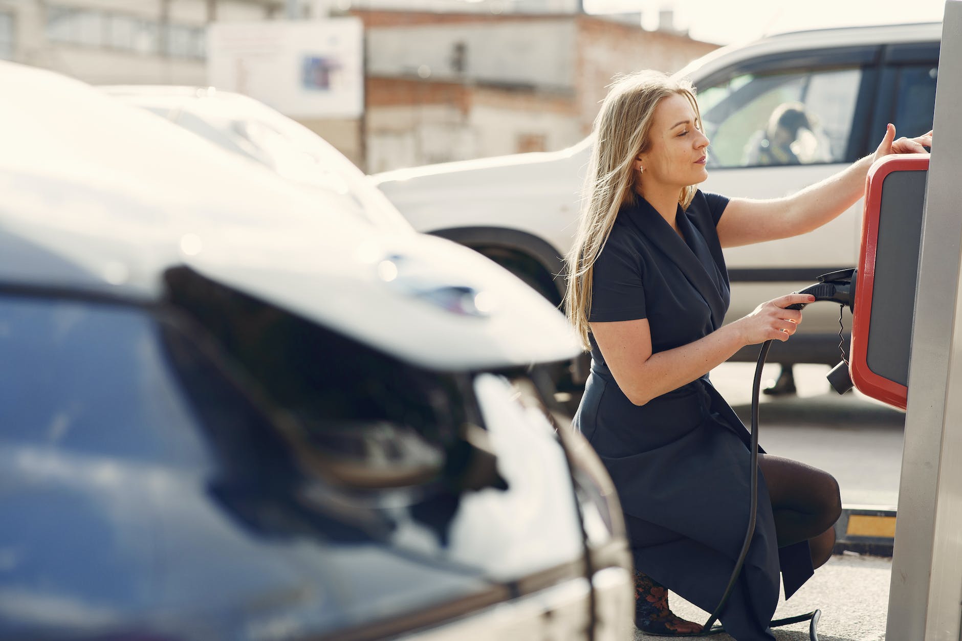 modern woman using station for charging electromobile