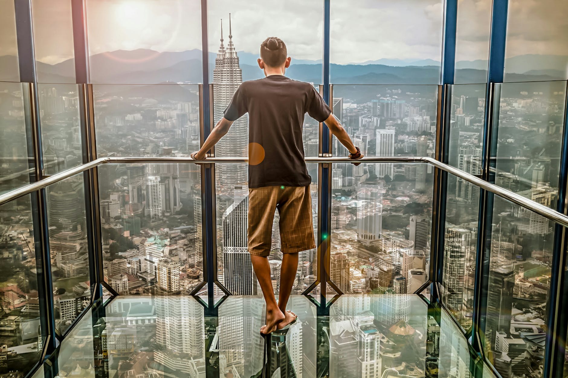 man in black t shirt looking out of glass windows during sunset